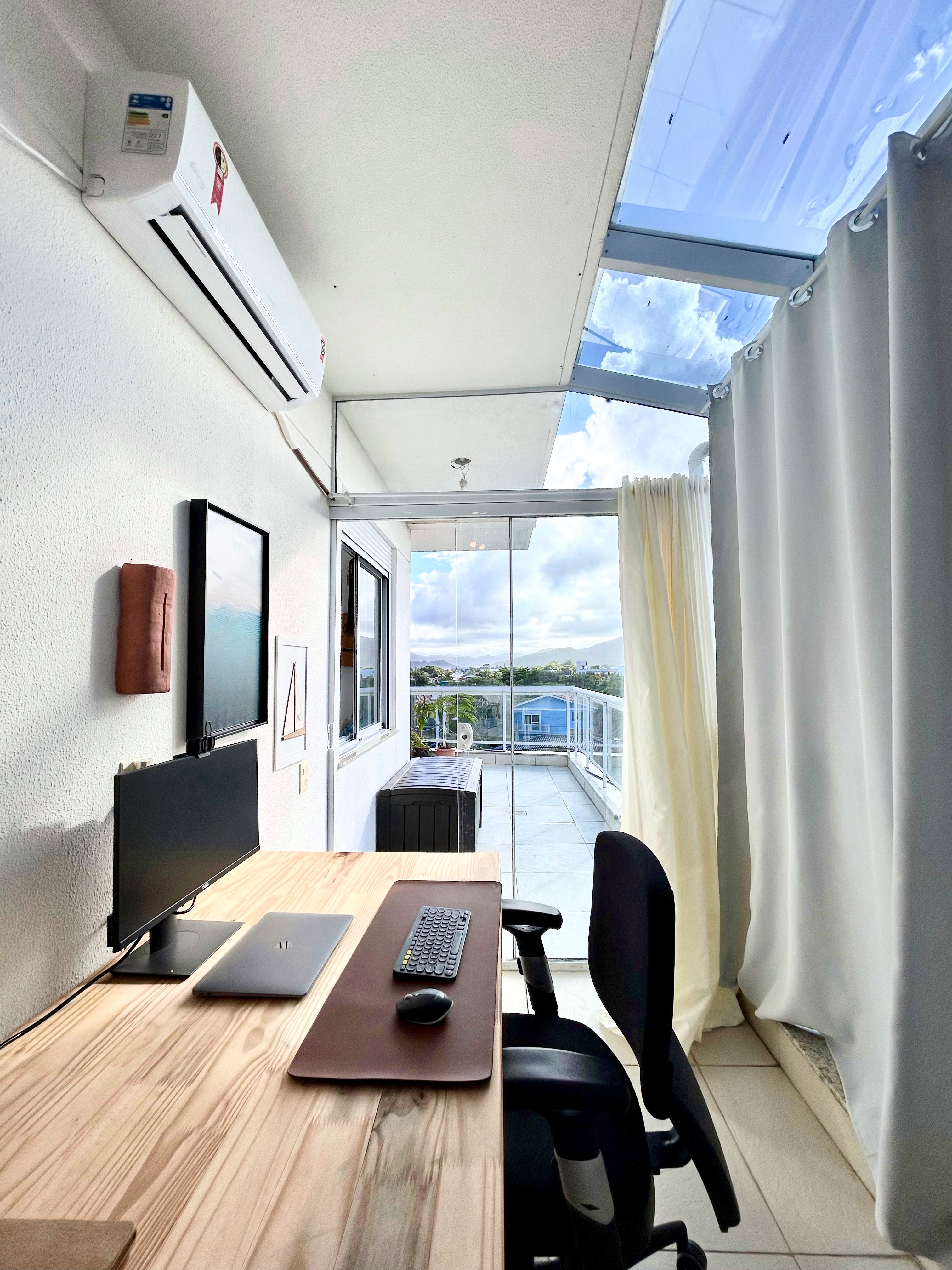 Escritório home office com claraboia, mesa de madeira e vista para o terraço na cobertura Campeche Florianópolis