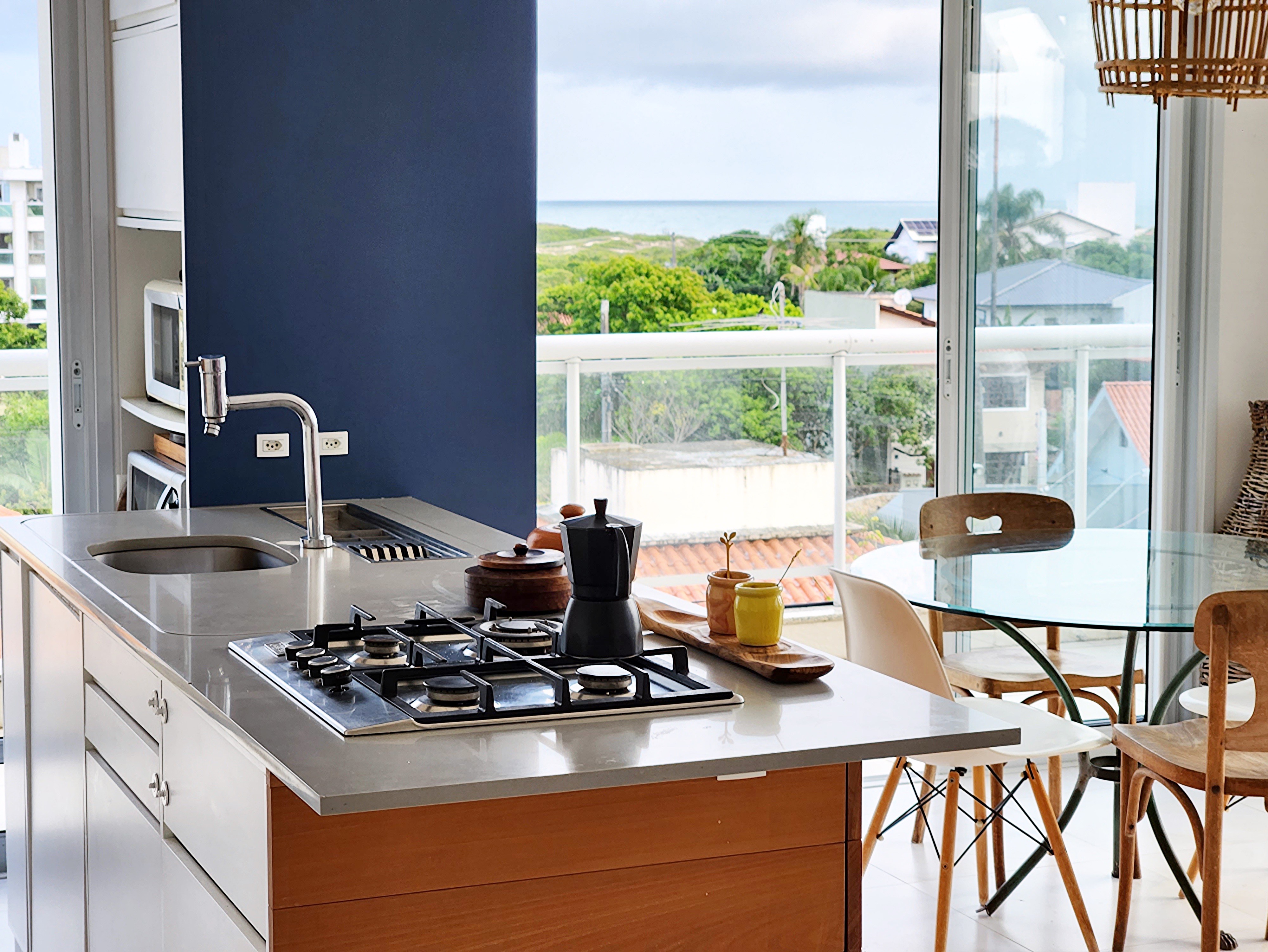 Cozinha gourmet integrada com ilha central, cooktop 5 bocas e bancada em inox na cobertura Campeche Florianópolis