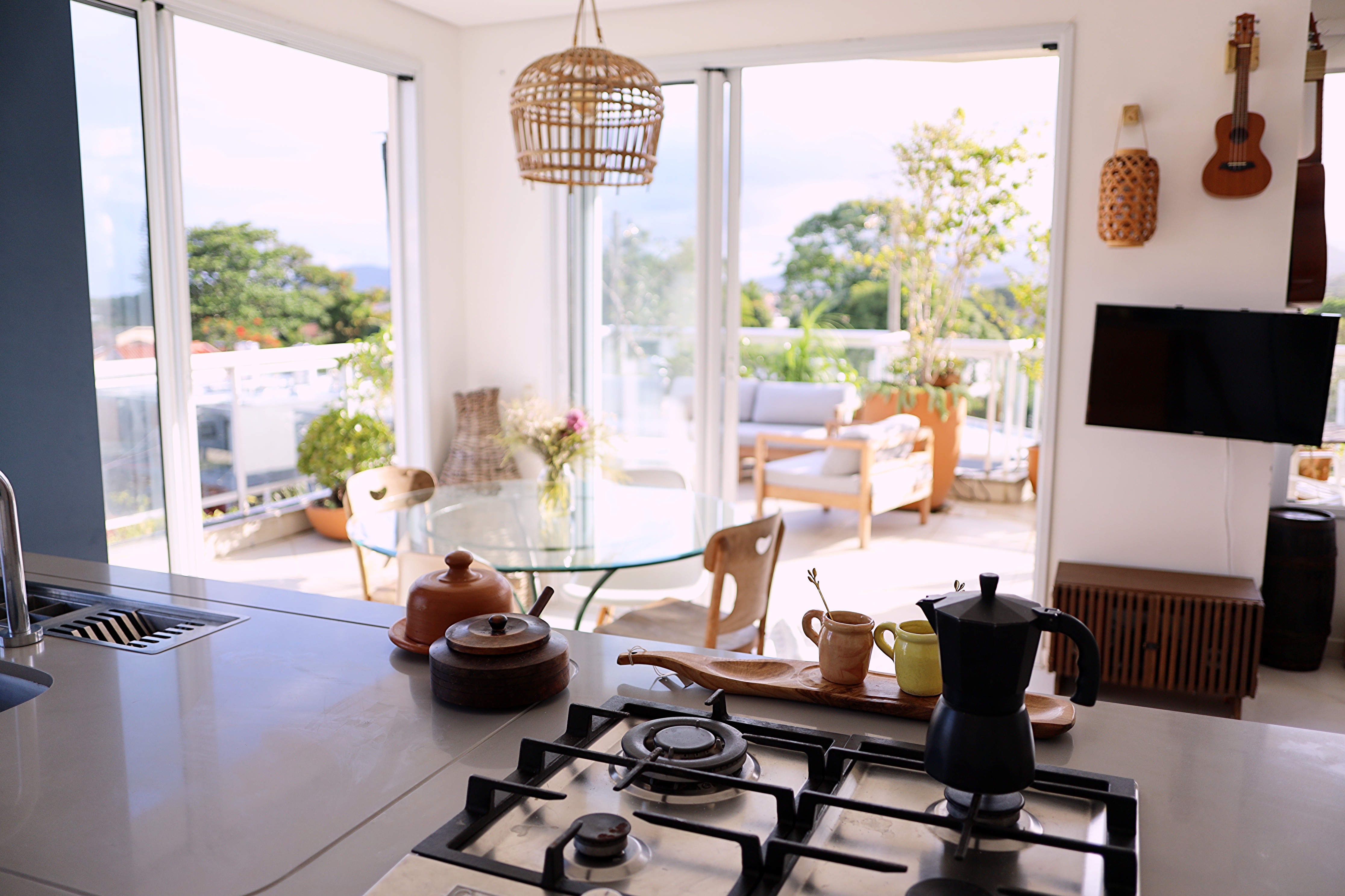Sala e cozinha integradas da cobertura no Campeche com ilha gourmet, cooktop e vista para o terraço em Florianópolis