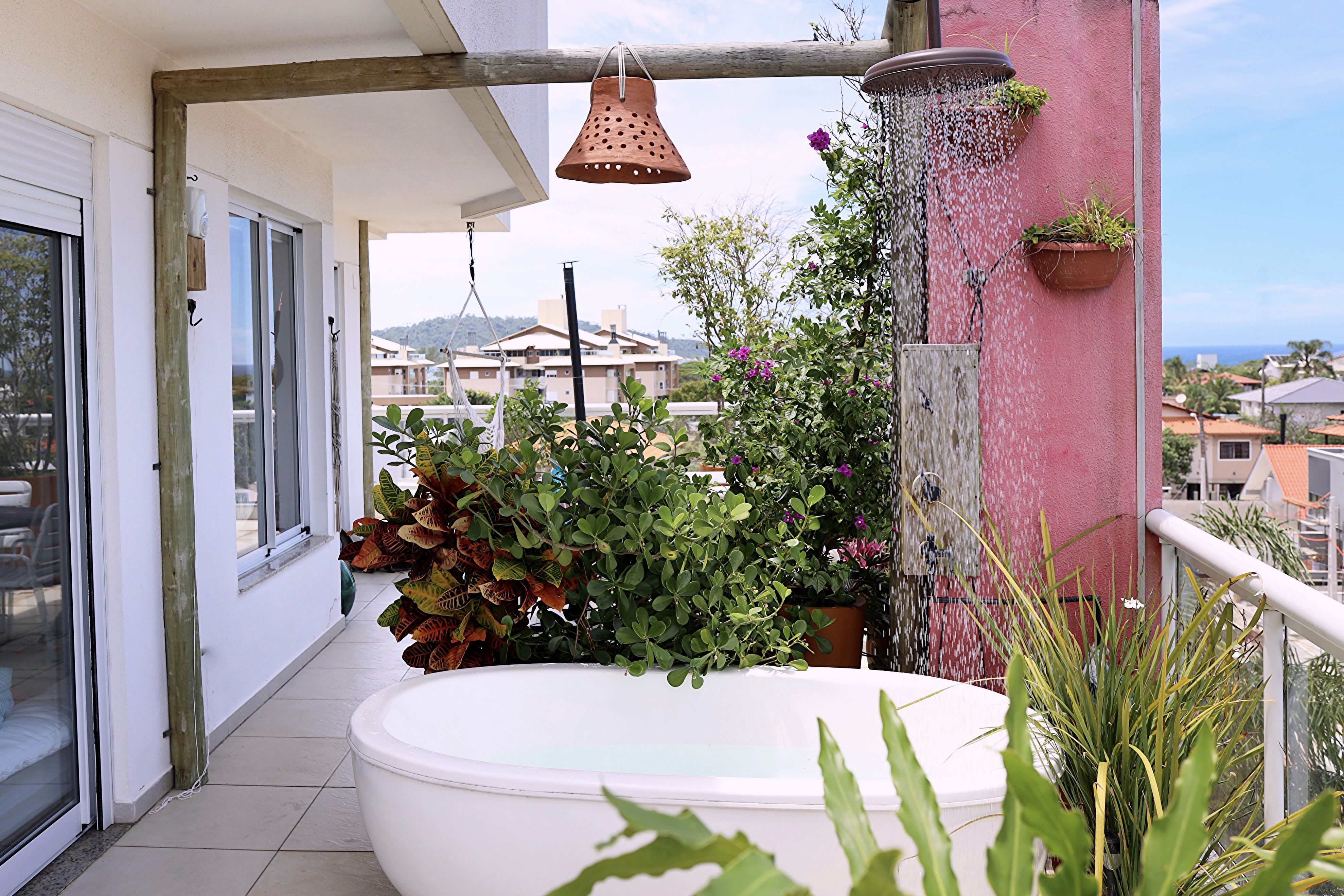 Banheira ao ar livre no terraço da cobertura com chuveiro e plantas tropicais no Campeche Florianópolis