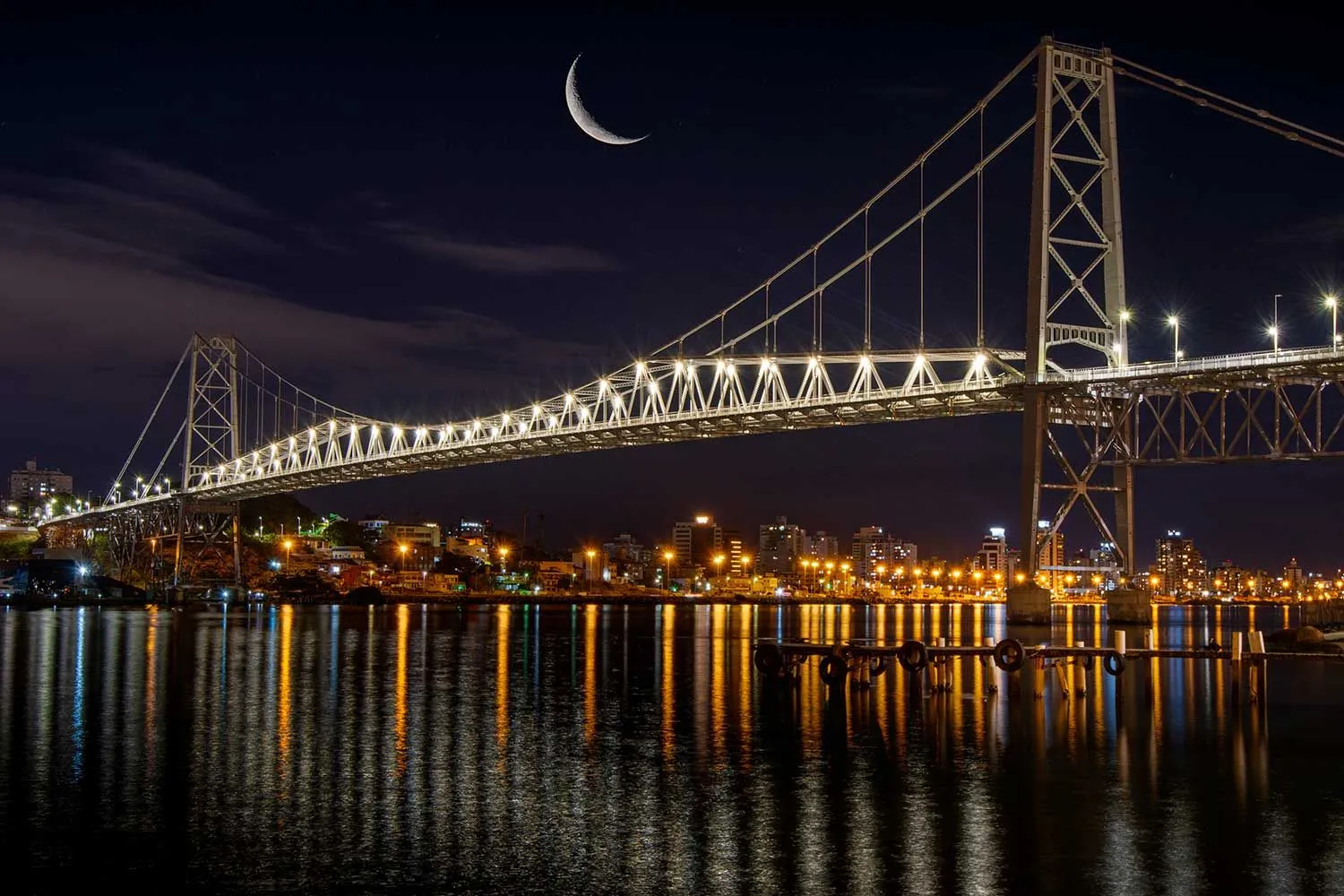 Ponte Hercílio Luz iluminada à noite com lua crescente em Florianópolis SC